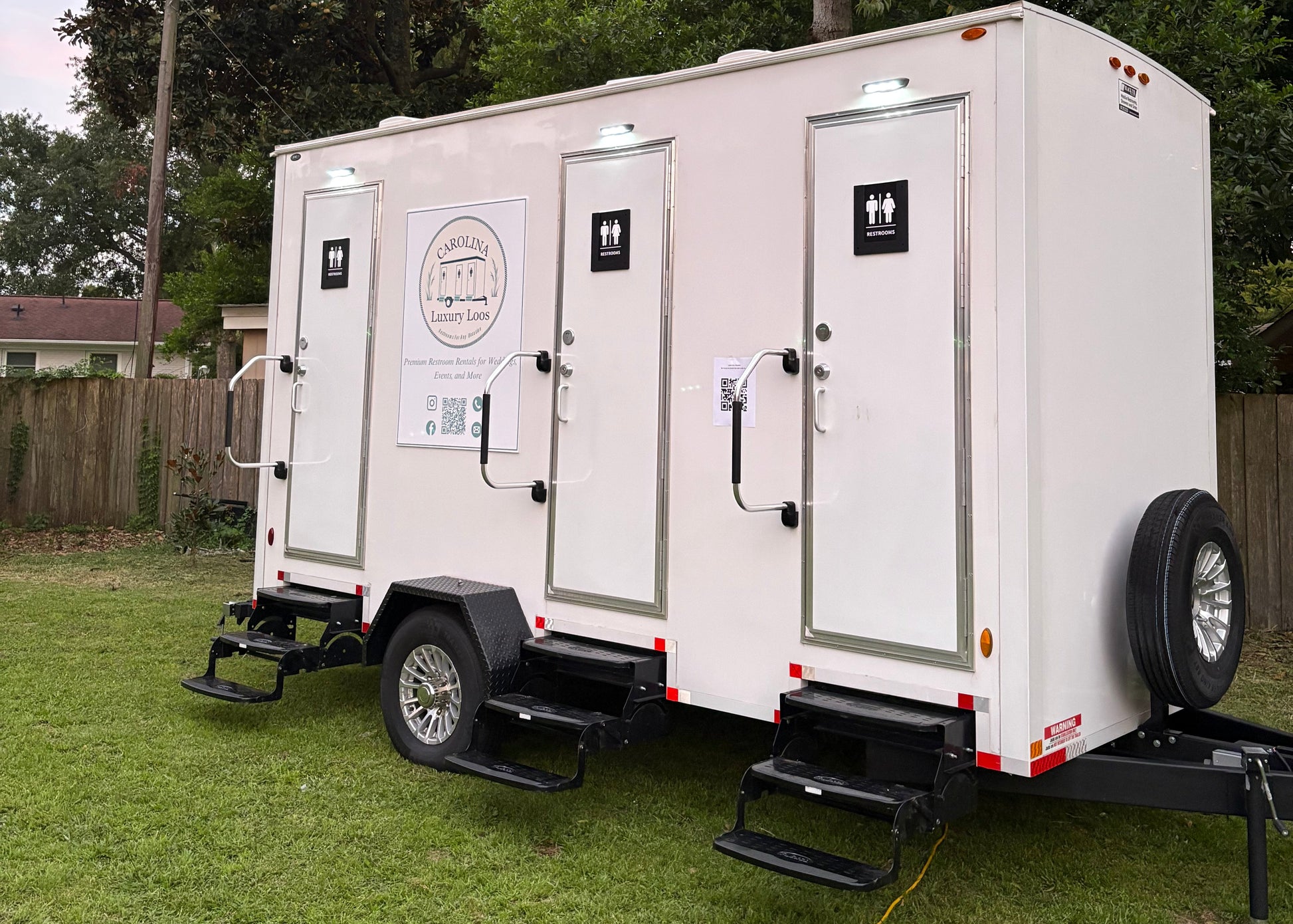 3-stall luxury restroom trailer by Carolina Luxury Loos, featuring private entrances, steps, and company branding, available for event rentals in North and South Carolina.